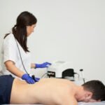 A female physiotherapist giving diathermy treatment on the patient's back 